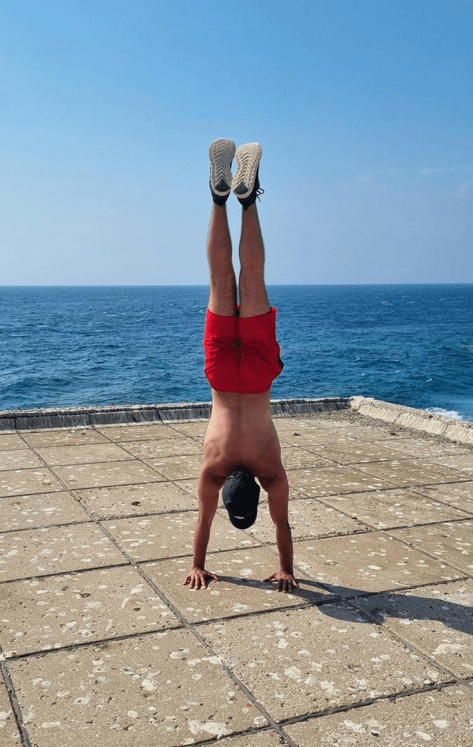 Charbel doing a handstand beside the Mediterranean